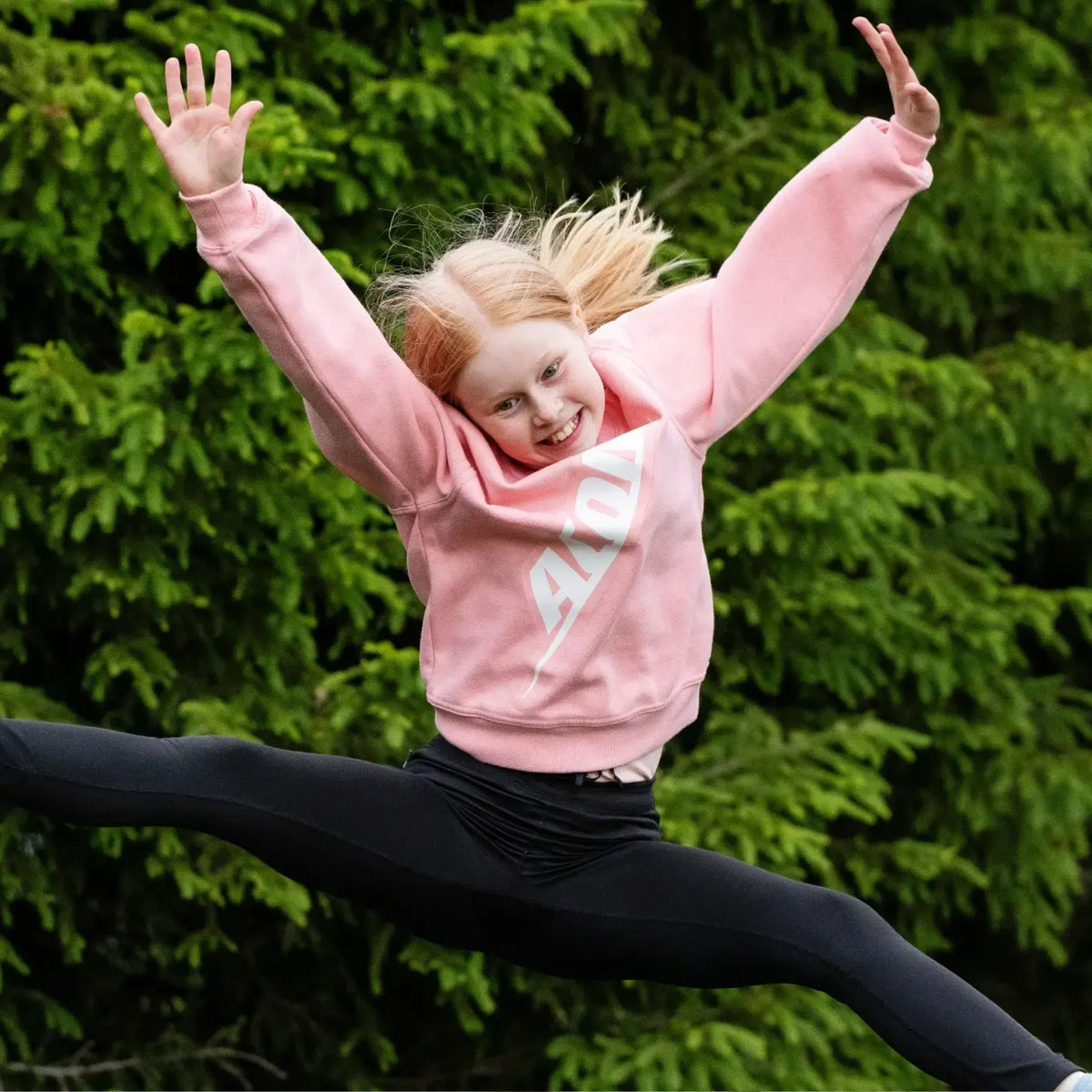 Kind hüpft auf Trampolin mit Rosa ACON Pullover