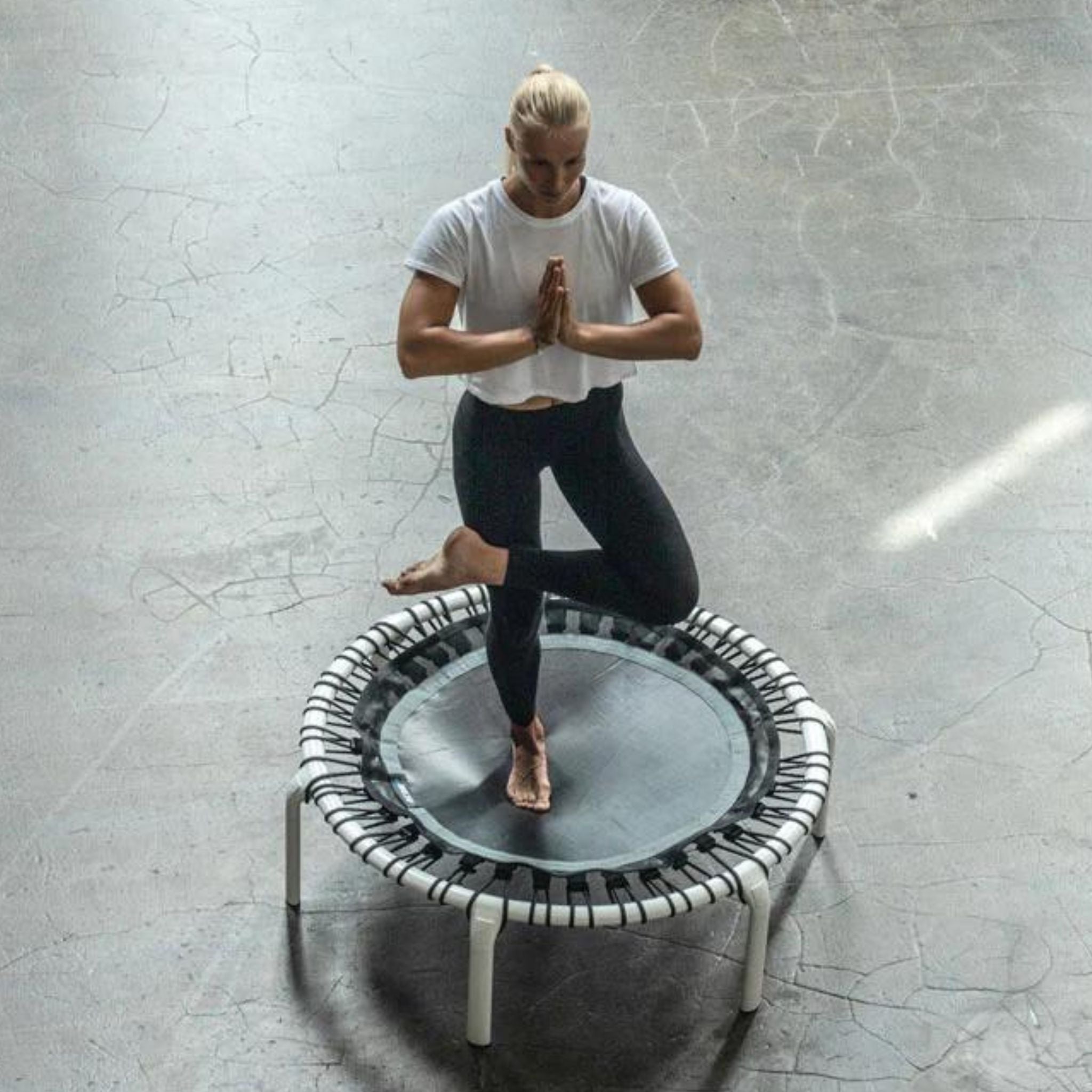 Frau macht Yoga-Pose auf einem Trampolin 