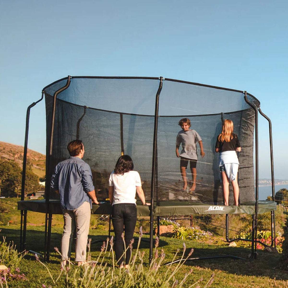 Familie mit Hund auf Trampolin im Garten
