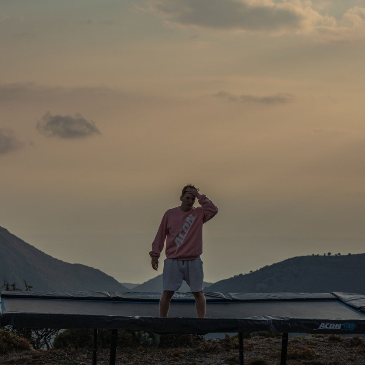 Mann steht auf einem Trampolin im Sonnenuntergang