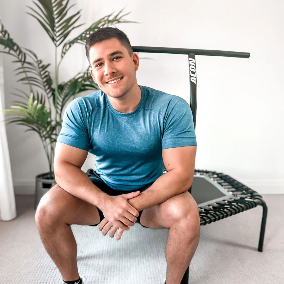 Man mit blauem T-Shirt sitzt auf ACON Trampolin