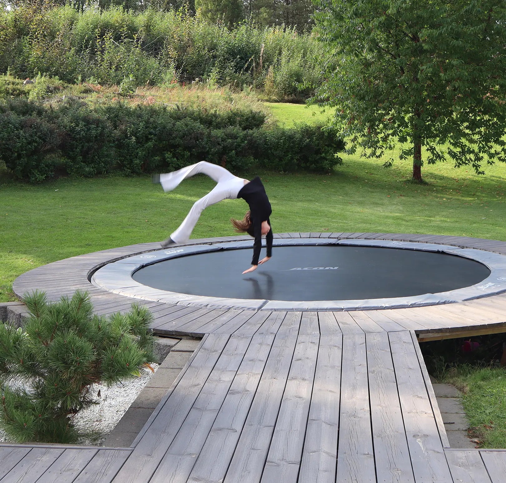 Ein Mädchen springt auf einem Trampolin, das in die Terrasse im Hinterhof eingebaut ist.