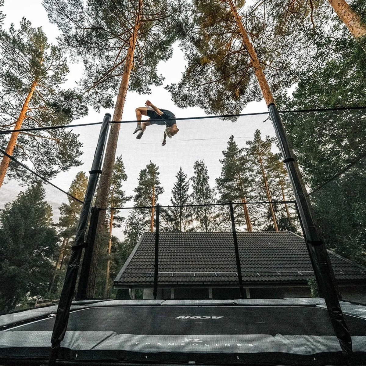 Mann macht einen Backflip auf einem Trampolin im Garten 