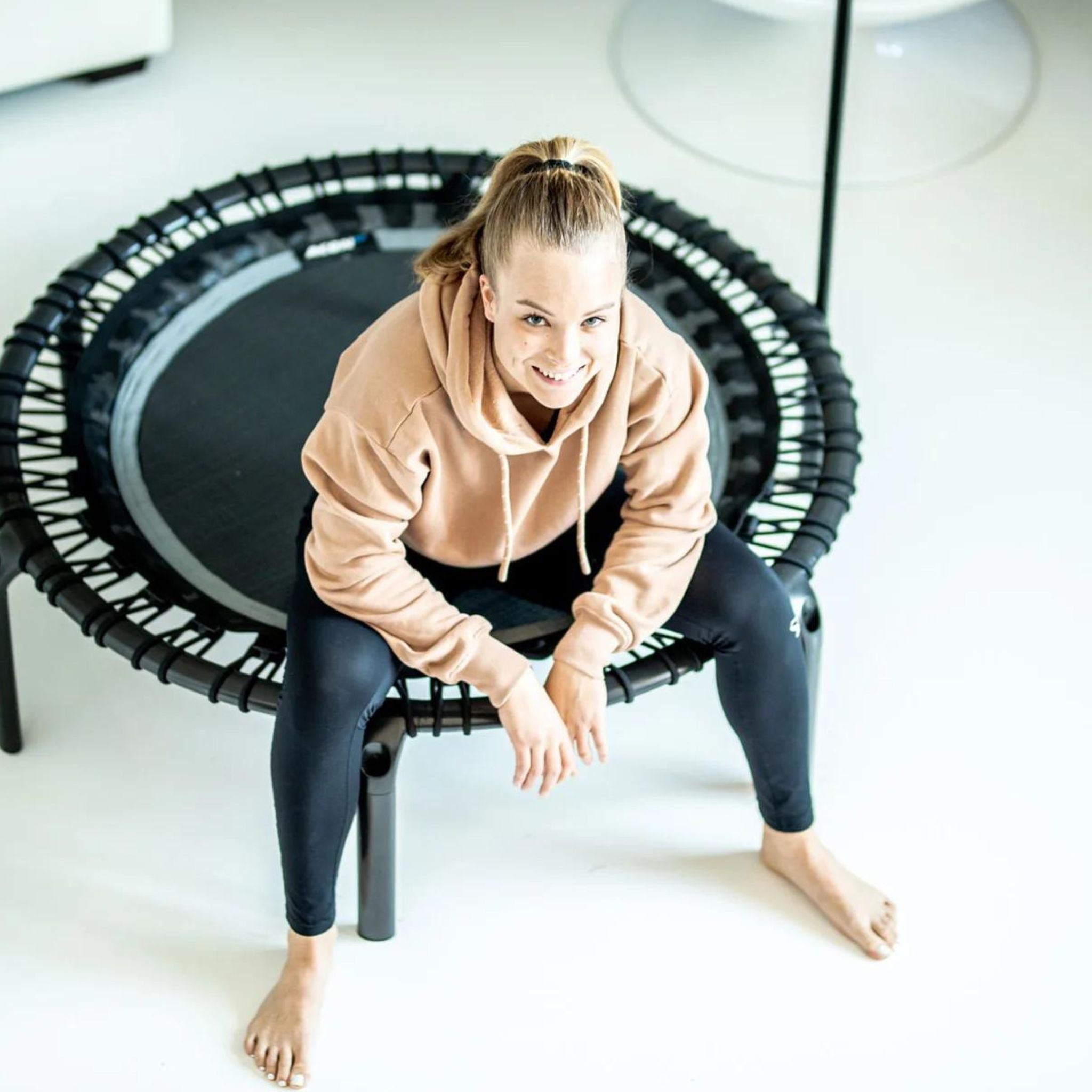 Schwangere Frau sitzt auf einem Trampolin