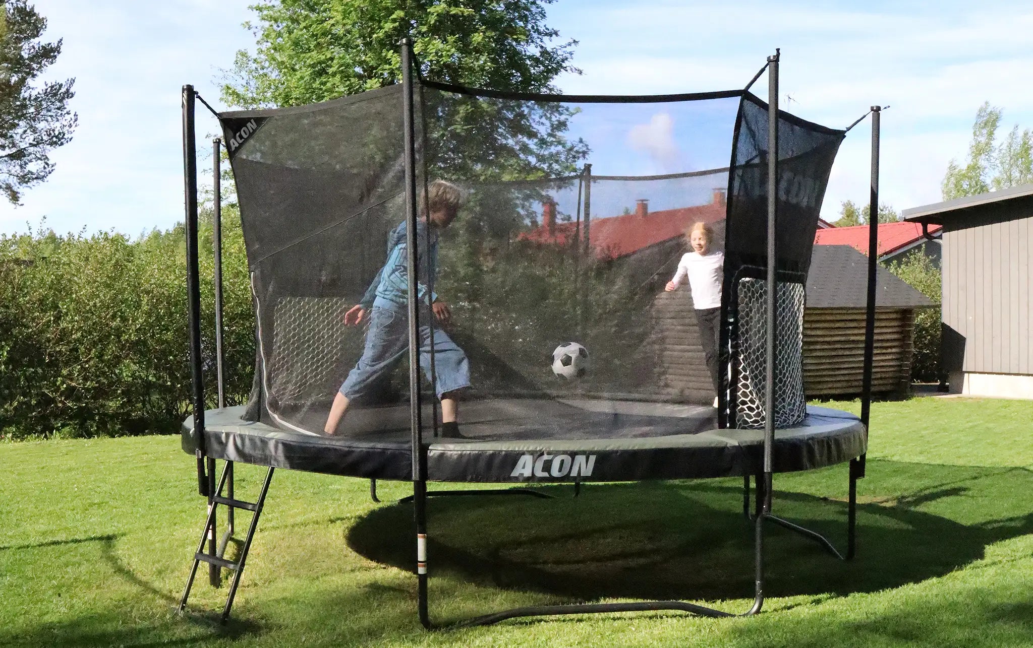 Zwei Kinder spielen Fußball auf Acon Trampolin mit Tor im Garten.