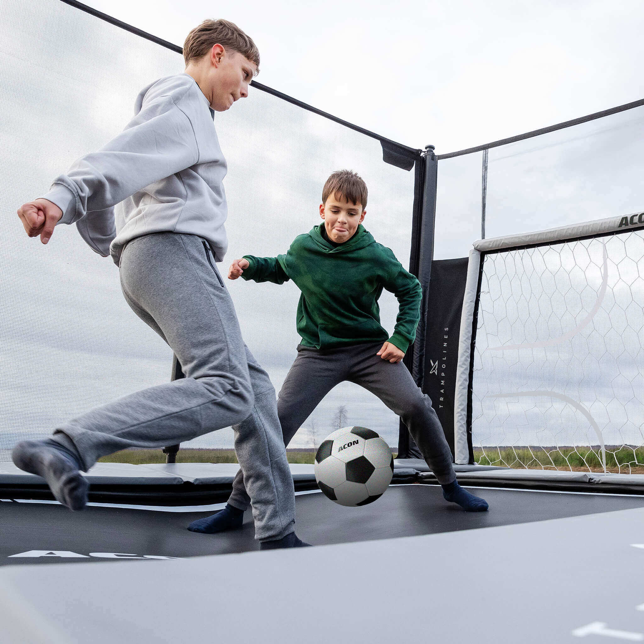 Zwei Jungen spielen Fußball auf einem Acon X 17 Trampolin mit Fußballfarbe