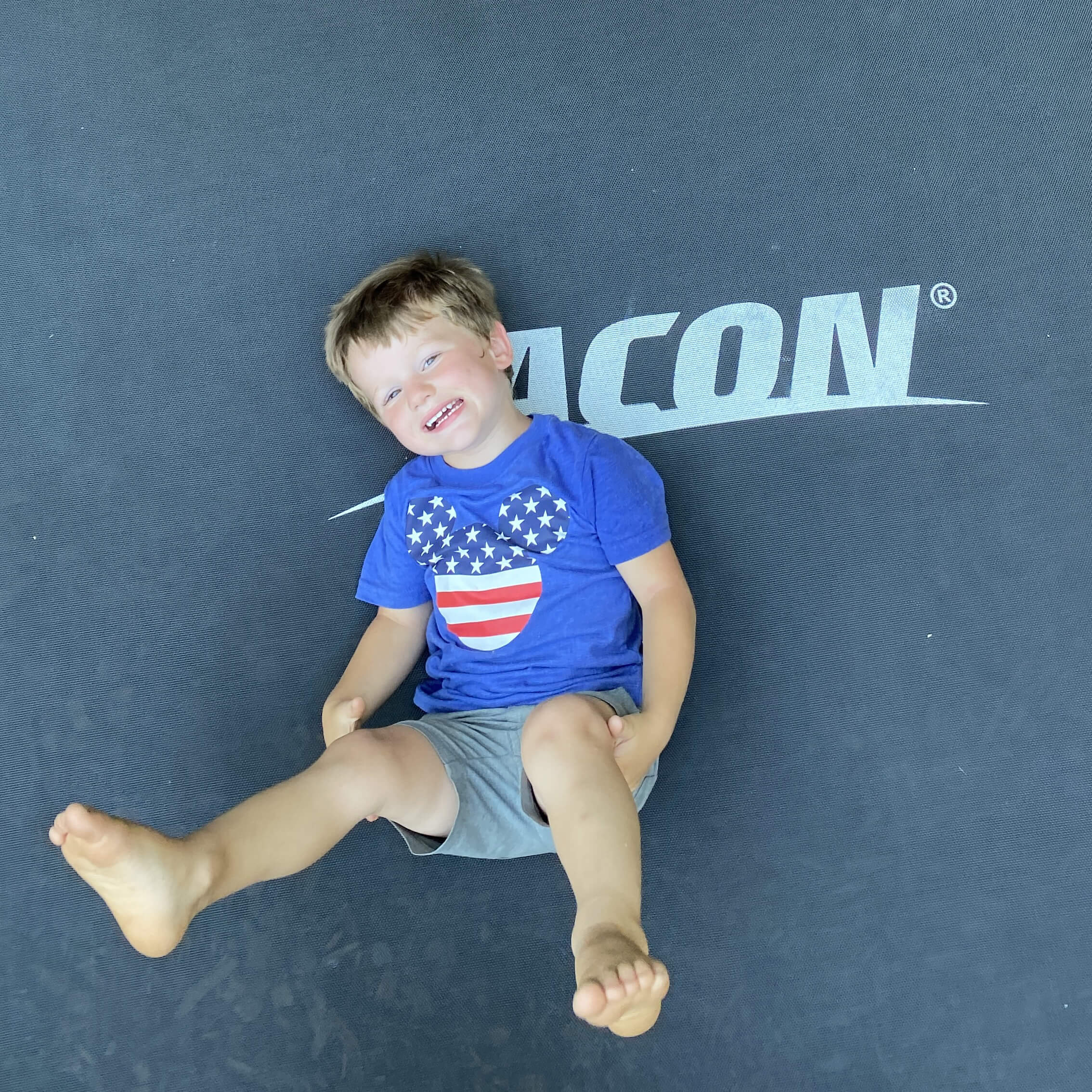 Ein glücklicher Junge liegt auf einem Acon Trampolin.