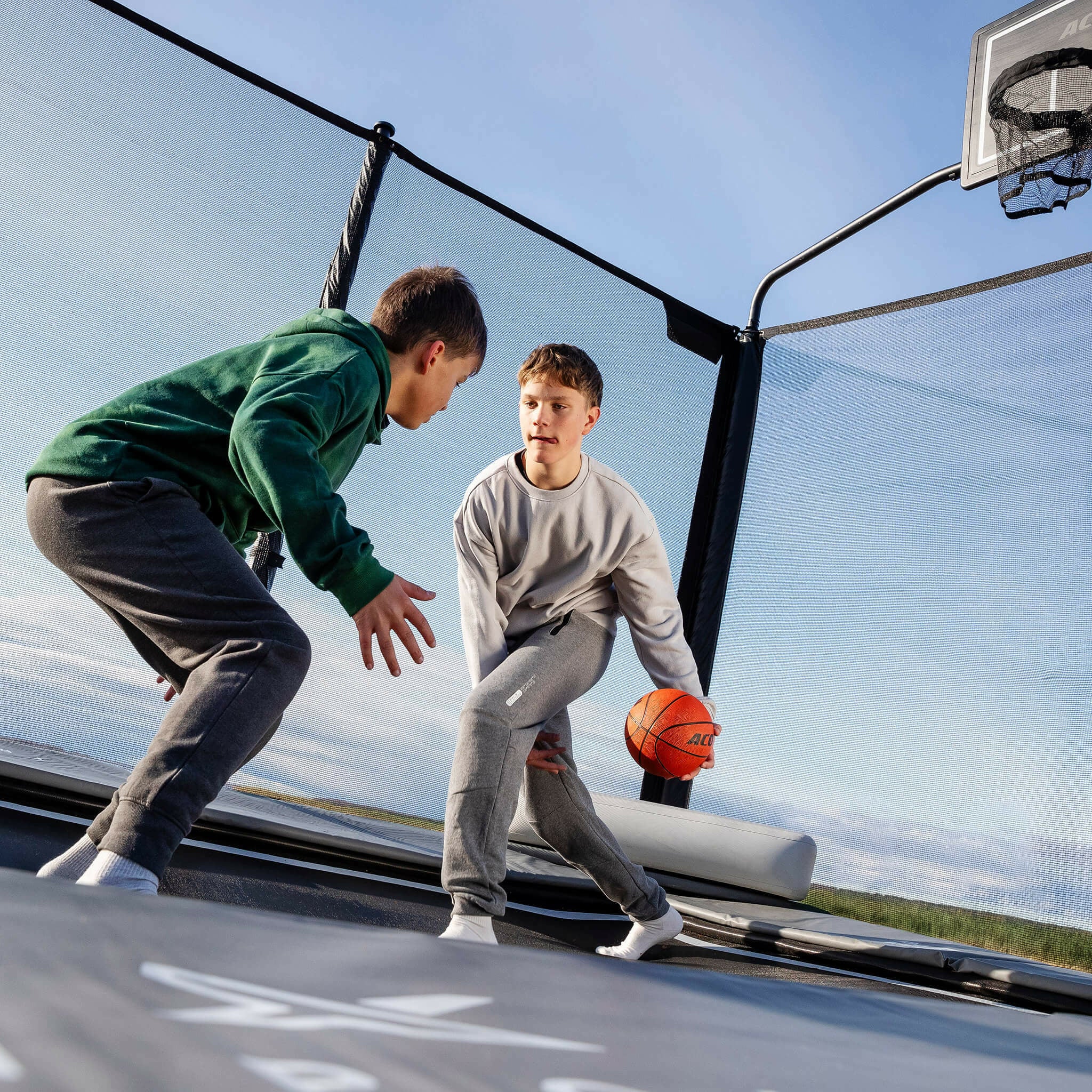 Zwei Jungen spielen Basketball auf dem Acon X Trampolin.